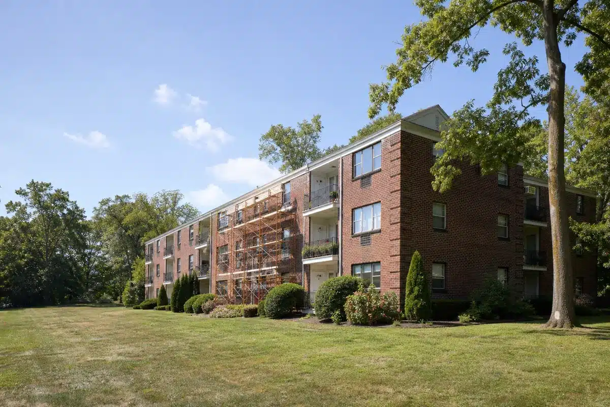 Three-story brick apartment building with scaffolding on one section during exterior renovation